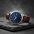 Elegant luxury stainless steel watch with leather strap on dark slate surface